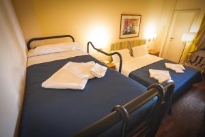 two beds in a hotel room with towels on them at Hotel Posta in Cecina