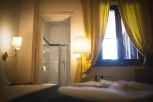 a room with a bed and a window and a lamp at Hotel Posta in Cecina