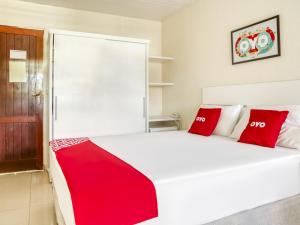 1 dormitorio con 1 cama blanca grande con almohadas rojas en OYO Hotel Stella Maris - Salvador, en Salvador