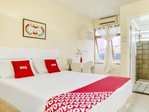 um quarto com uma grande cama branca com almofadas vermelhas em OYO Hotel Stella Maris - Salvador em Salvador