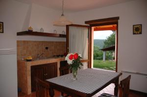 a kitchen with a table with a vase of flowers on it at Agriturismo Poggio Corbello in La Pesta