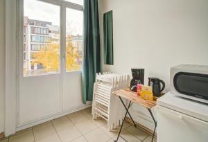 een keuken met een magnetron en een tafel en een raam bij The National Lodge in Antwerpen +5 foto's