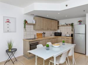 uma cozinha com uma mesa branca e um frigorífico branco em The Green Garden Suite by the Beach em Herzeliya