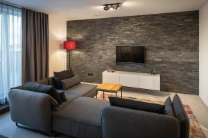 Ein Wohnzimmer mit zwei Sofas und einem Fernseher an einer Backsteinwand in der Unterkunft Home & Work in Pulheim