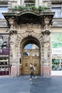 une personne marchant devant un bâtiment avec une porte dans l'établissement BpR Colorist Apartments, à Budapest