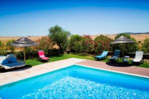 a swimming pool with chairs and umbrellas in a yard at Casa dos Castelejos in Guerreiro