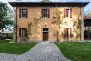 une maison avec des fenêtres à volets rouges et une allée dans l'établissement Bilocale nel Parco di Villa Erba, à Cernobbio
