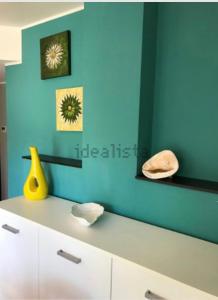 ein Zimmer mit blauen Wänden und einer Theke mit einer gelben Vase in der Unterkunft Casa vacanze “Perla del Circeo” in Sabaudia