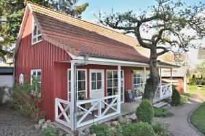 eine rote Scheune mit weißen Türen und einem Baum in der Unterkunft PW Lütt Drosselhörn 1 in Laboe