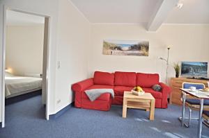 uma sala de estar com um sofá vermelho e uma cama em Panorama 1 em Laboe