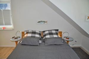 ein Bett mit zwei Kissen und zwei Tischen in einem Zimmer in der Unterkunft Villa Bellevue II in Heikendorf