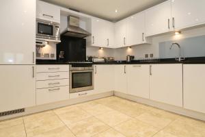 an empty kitchen with white cabinets and appliances at BEACHSIDE SPACIOUS apartment, private garden in St Merryn