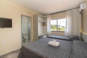 a hotel room with two beds and a window at Pousada Espindola in Penha