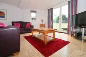 a living room with a coffee table and a tv at BEACHSIDE SPACIOUS apartment, private garden in St Merryn