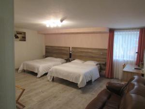 Habitación de hotel con 2 camas y sofá en Le Relais De La Poste, en Pithiviers