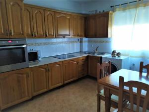 cocina con armarios de madera, mesa y microondas en Apartamento Villa Soterraña, en Trujillo