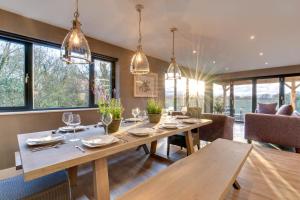 a dining room with a table and chairs and windows at Cleabarrow Cottage in Windermere