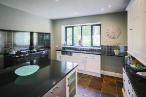 a large kitchen with black countertops and white cabinets at Cherry Trees in Windermere