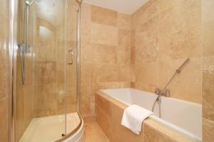 een badkamer met een douche, een bad en een wastafel bij BY THE BEACH, spacious apartment in Saint Merryn