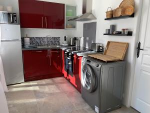 uma cozinha com armários vermelhos e uma máquina de lavar roupa em Solimany em Saint-Gilles