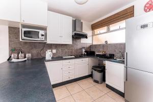 a kitchen with white cabinets and a refrigerator at Amazing Sea View Apartment La Ballito in Ballito +7 photos