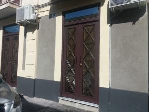 una porta marrone sul lato di un edificio di CIVITAS a Catania