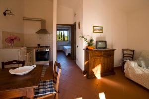 cocina y sala de estar con mesa y TV en Agriturismo Poggio Corbello, en La Pesta