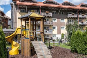 einen Spielplatz vor einem großen Gebäude in der Unterkunft Adler ClubResidence in Moena