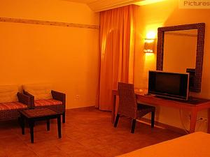 Habitación de hotel con TV y escritorio con sillas. en Sahara Douz, en Douz