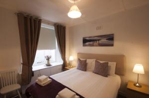 a bedroom with a white bed with a window and a lamp at Allan Stream Apartment in Bridge of Allan