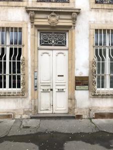 ナンシーにあるLe Petit Carrièreの窓が2つある建物の白い扉