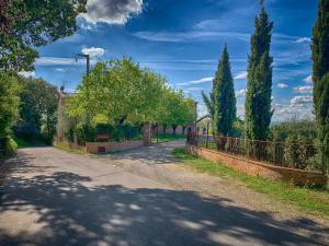 una carretera con una valla y árboles en el lateral en Casale Cardini, en Foiano della Chiana