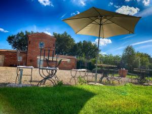an umbrella and some chairs and a table and benches at Casale Cardini in Foiano della Chiana