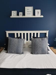 een bed met 2 kussens en een blauwe muur bij Seaside House Broadstairs by the Beach with Parking in Broadstairs