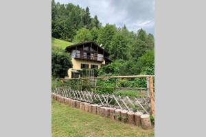 a house on the side of a hill with a fence at Paola’s Country Home - Vanoi Primiero Trentino in Canale San Bovo