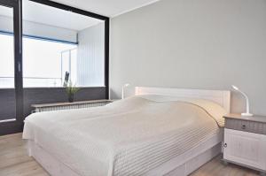 a bedroom with a white bed and a large window at BRN Fliegender Hollaender in Laboe
