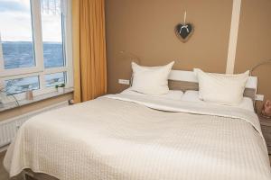 Schlafzimmer mit einem großen weißen Bett und einem Fenster in der Unterkunft Strandhotel 26 in Laboe