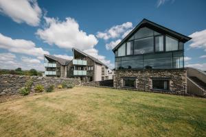 a house with glass windows and a stone wall at Carus House @ Carus Green in Kendal