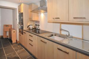 a kitchen with wooden cabinets and a sink at Kingsview Apartment in Stirling