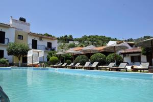 a large swimming pool with chairs and umbrellas at Yalis Studios in Achladies