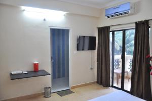 a hotel room with a tv and a bedroom at Ocean Crest Hotel in Colva