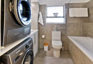 a bathroom with a toilet and a washing machine at Beachfront Apartment @ Morleenpark unit 11 in Swakopmund +14 photos