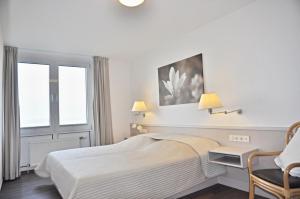 a white bedroom with a bed and a chair at Seeadler in Stein