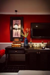 a room with a red wall with a desk with a television at Adora Art Hotel in Ho Chi Minh City