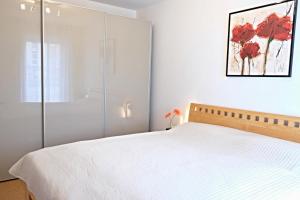 een slaapkamer met een wit bed met rode bloemen aan de muur bij Sommerbrise Wallbox in Laboe