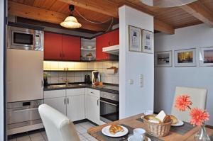 eine Küche mit roten Schränken sowie einem Tisch und Stühlen in der Unterkunft Windjammer: Passat in Laboe