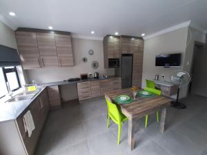 a kitchen with a wooden table and green chairs at Studio 4 The Studios at Churchill in Hillcrest +15 photos