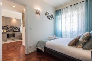 a bedroom with a bed with blue curtains and a kitchen at Bairrus Lisbon Apartments - Duque in Lisbon