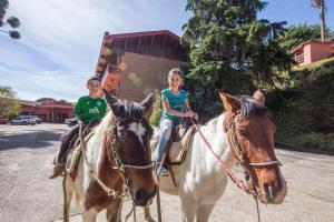 Un niño y una niña montando a caballo en Hotel Recanto São Cristóvão - Próximo ao Parque Tarundu, en Campos do Jordão