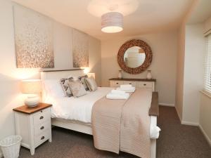 a bedroom with a white bed and a mirror at Kingfisher Cottage in Ilfracombe